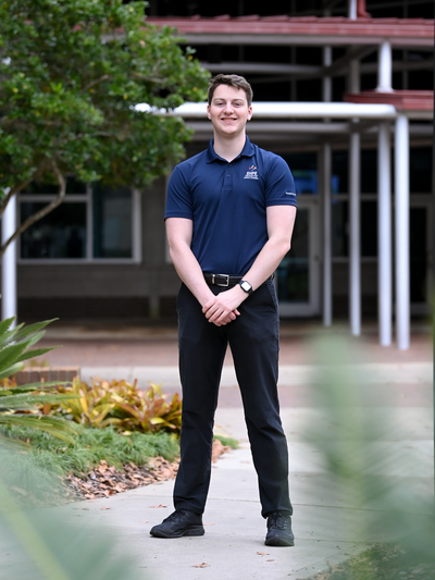 UNF senior Colin Ott standing in front of a campus builing