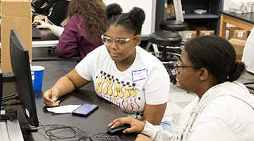 Two students working on dark matter data analytics on a computer