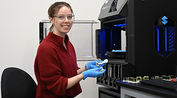 Molly Dobrow in front of a 3D printing machine