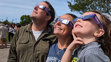 Family wearing eyewear looking up to the sky to view the total eclipse