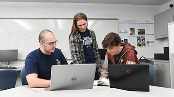 Furio Gerwitz, Troy Kidd and Jake Sutton posed around two open laptops