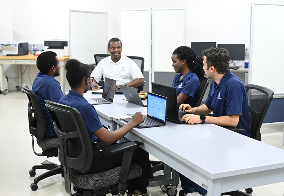 Dr. Thobias Sando sitting at a round table with his student team