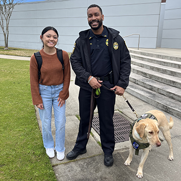 UNF student, Sophia Velasco, posing with an officer and his station dog
