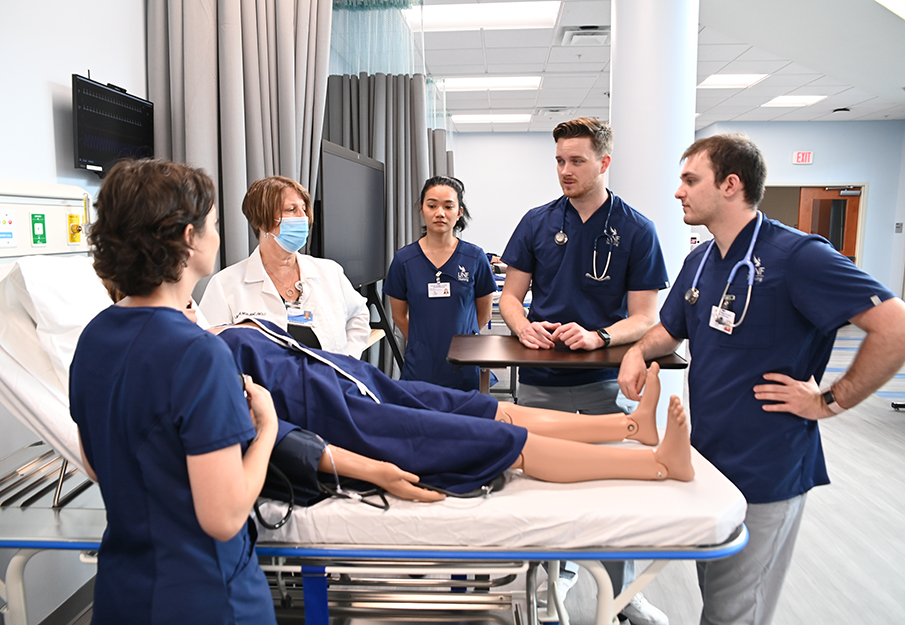 MedNexus nursing students and professor surrounding a dummy patient