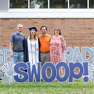 Mariah Glomb posing with her family in her cap and gown