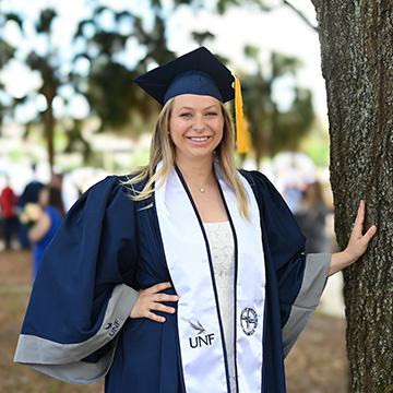 Mariah Glomb posed next to a tree in her cap and gown