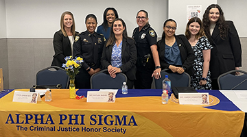 Gabriella Marquez standing with other members of Alpha Phi Sigma at an information table