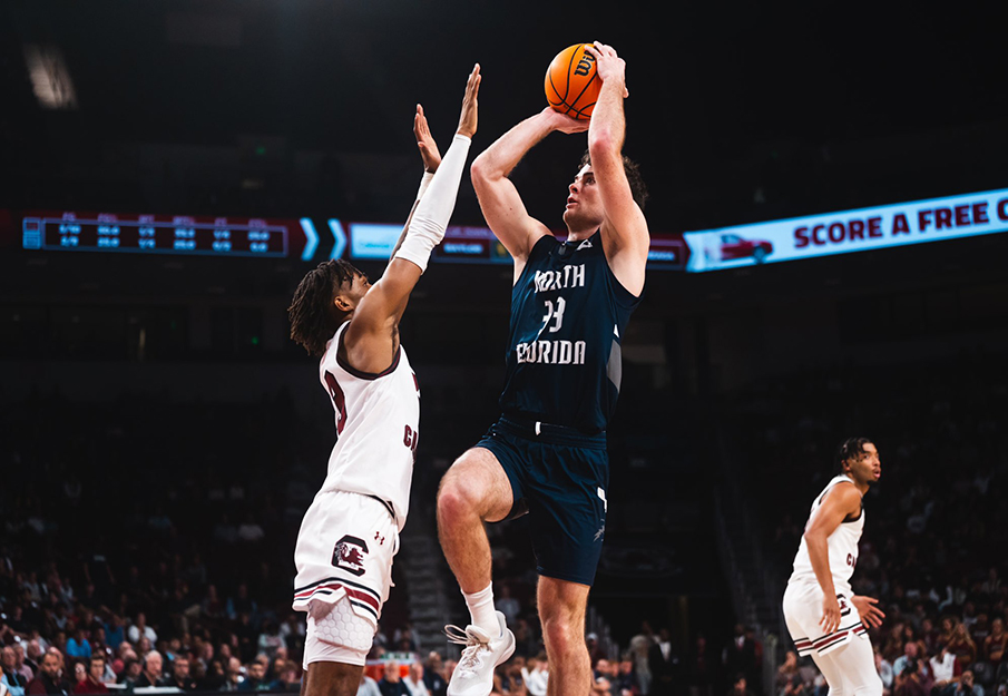 UNF men's basketball player number 33 throwing a basketball while South Carolina player tries to grab it