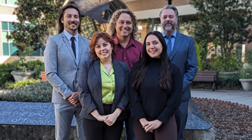 Public Opinion Research Lab staff standing in front of globe on campus