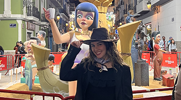 Carmen Rodriguez holding the brim of her hat in front of a statue in Valencia, Spain