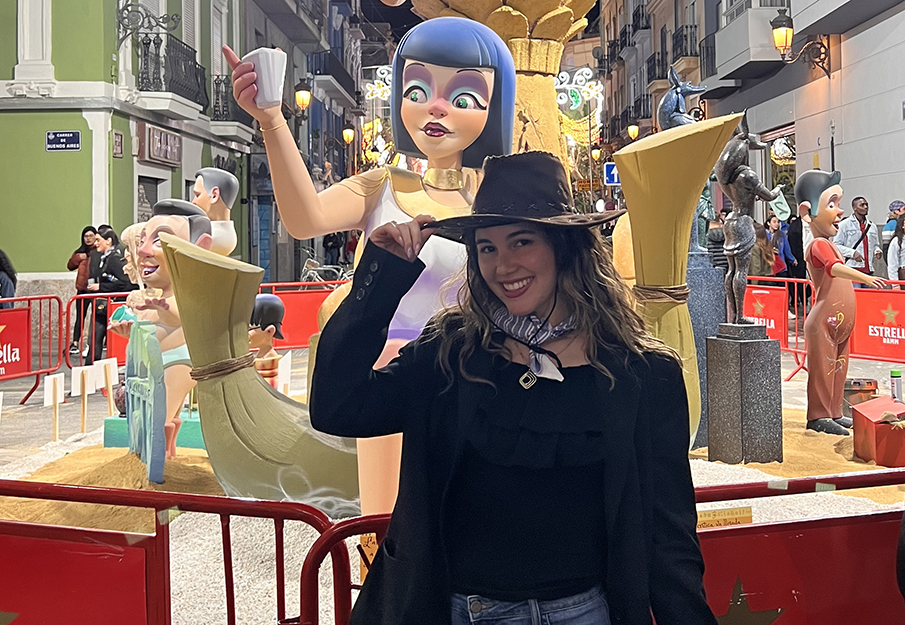 Carmen Rodriguez holding the brim of her hat in front of a statue in Valencia, Spain