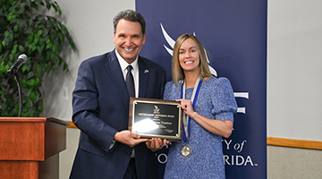 Heather Barnes Truelove and President Moez Limayem posing together holding a plaque inscribed with her award 