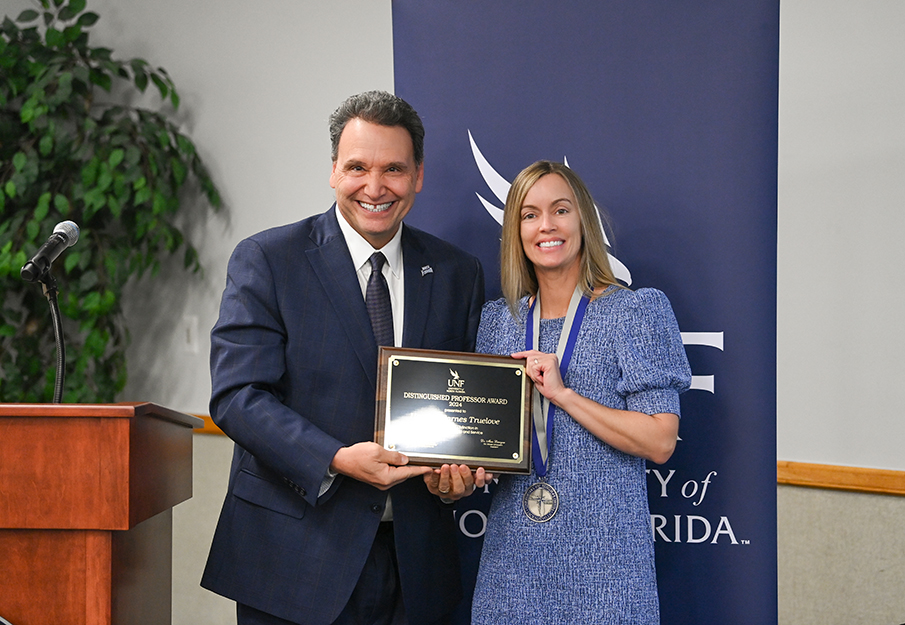 Heather Barnes Truelove and President Moez Limayem posing together holding a plaque inscribed with her award