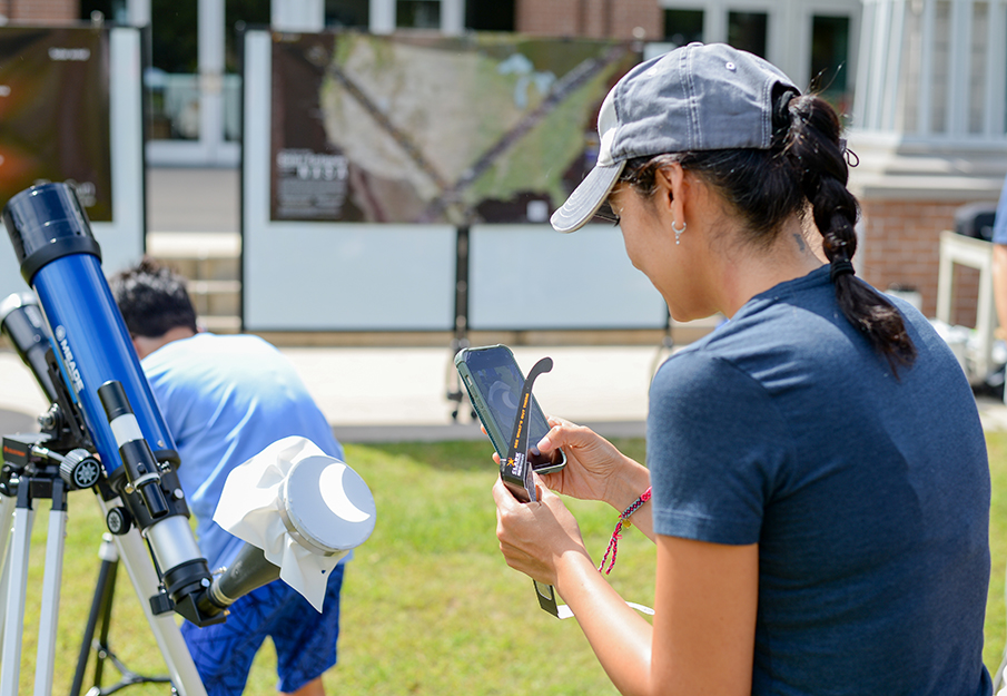 Girl taking a photo of the reflection of an eclipse