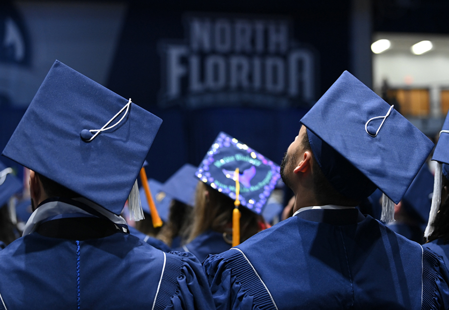 Two graduates standing with backs to camera with focus on their caps