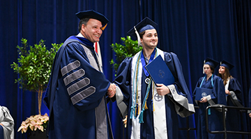 UNF President Moez Limayem shaking a graduating student's hand