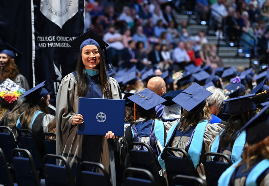 UNF Graduate student holding her diploma at commencement