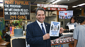 University of North Florida President Moez Limayem at Angie's Subs posing with a flyer for the SWOOP Sub
