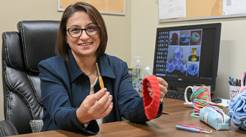 Beyza Aslan sitting at her desk holding knitting tools