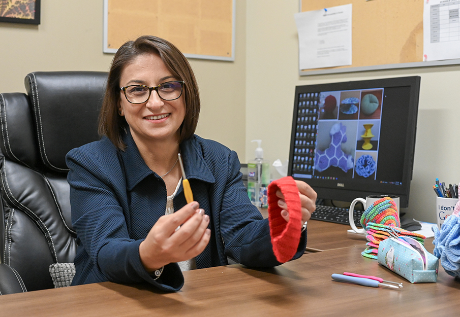 Beyza Aslan sitting at her desk holding knitting tools