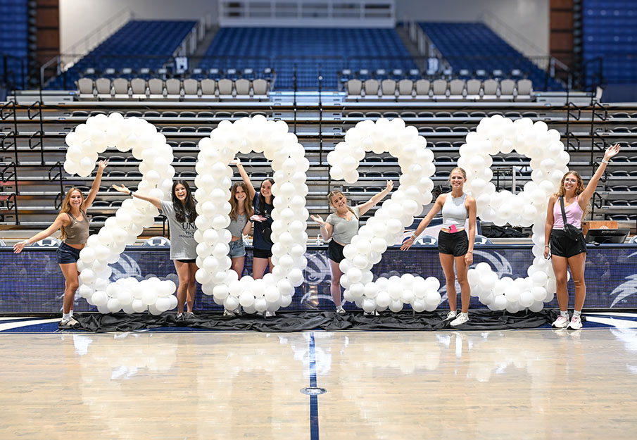 Seven freshmen posing next to a 2029 balloon sign