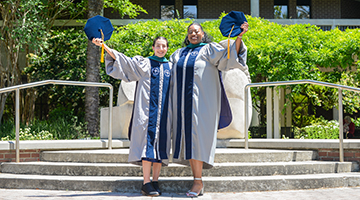 Gianna Forte and Shekinah Mitchell holding their caps