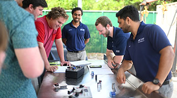 early-career apprentices and UNF students standing around a table