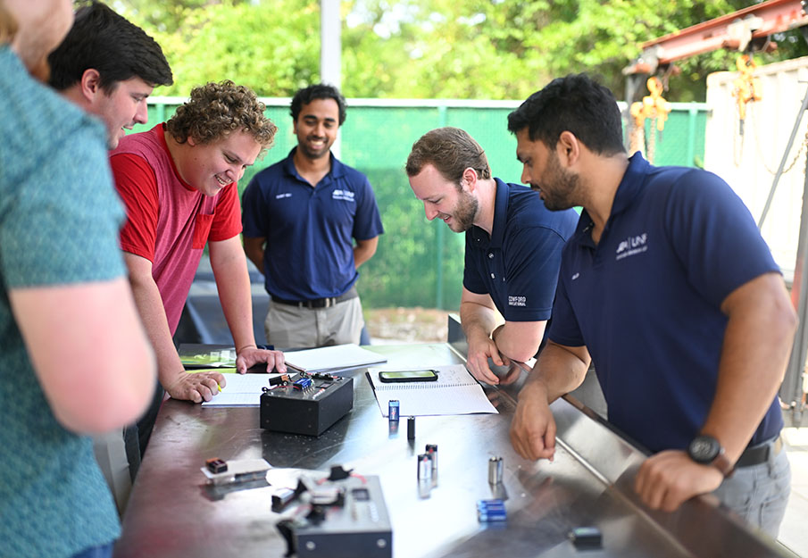 early-career apprentices and UNF students standing around a table