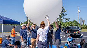 Some of the students adding helium to the balloon they will launch
