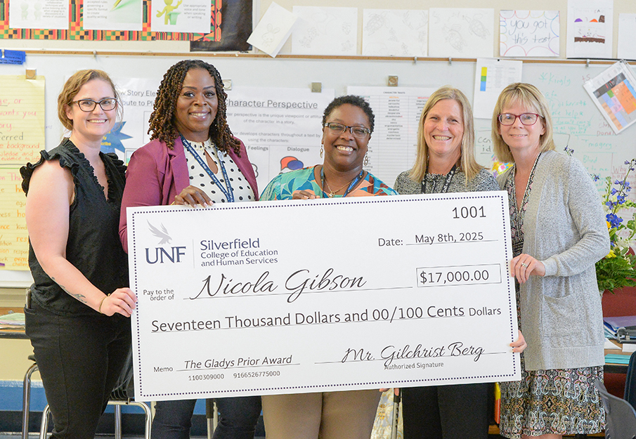 Nicola Gibson holding her check with co-teachers