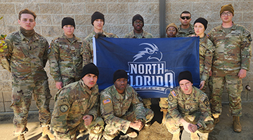 UNF ROTC team posing with a UNF branded flag