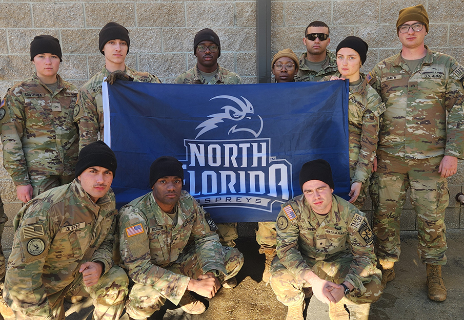 UNF ROTC team posing with a UNF branded flag