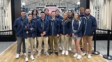 A group of UNF students who volunteered at THE PLAYERS Championships standing in front of the Fan Shop