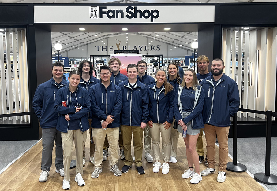 A group of UNF students who volunteered at THE PLAYERS Championships standing in front of the Fan Shop