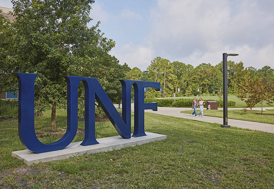 UNF letters with two students walking in background
