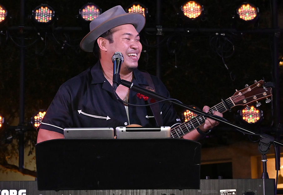 Andrew Sabin sitting behind a keyboard holding a guitar