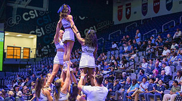 Cheerleaders on pyramid performing in front of crowd