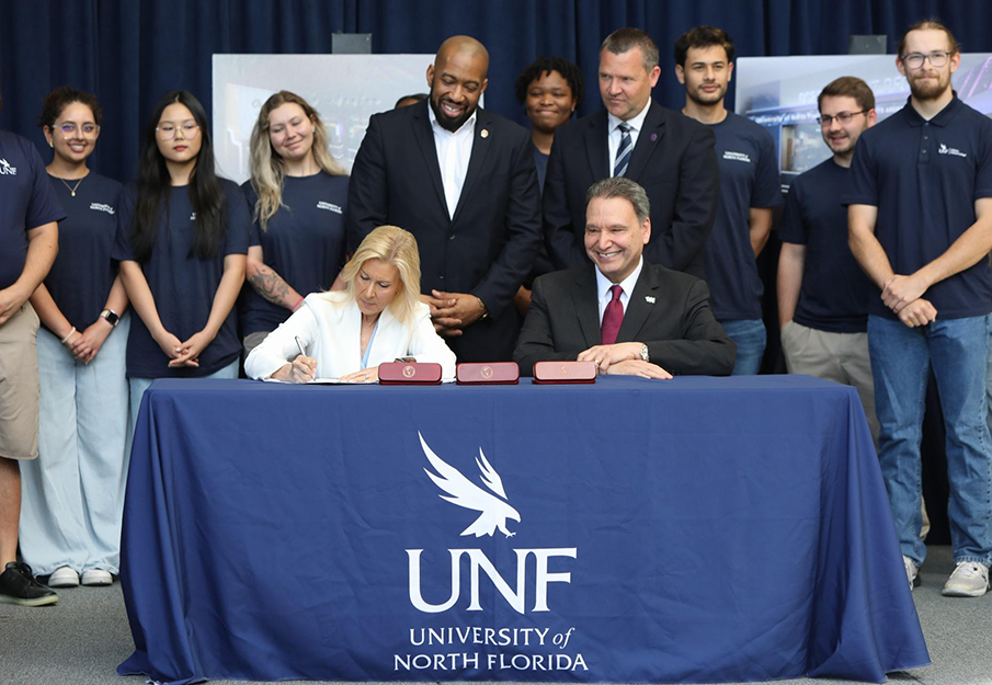 Mayor Donna Deegan signs bill for new UNF esports arena, sitting next to President Moez Limayem