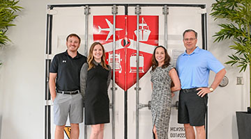 Tom Piatak and his family standing in front of doors with Magellan logo