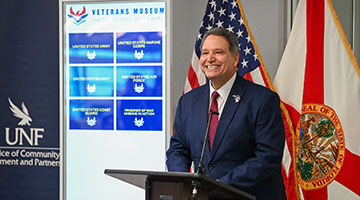 President Moez Limayem at podium in front of new kiosk