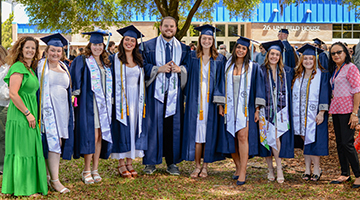 A group of UNF graduating seniors standing next to faculty