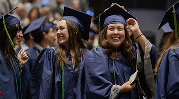 Two UNF graduates excitedly walking to their seats at commencement ceremony
