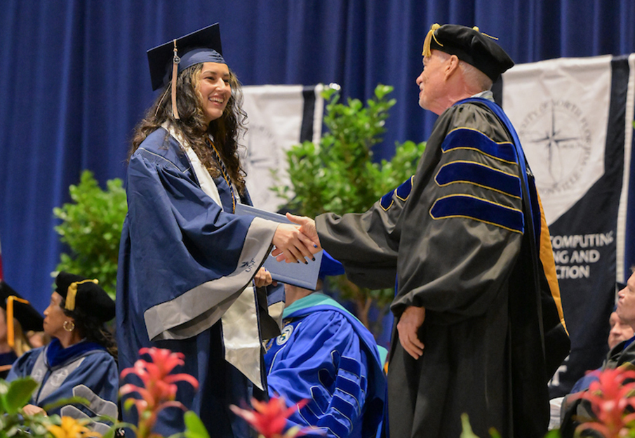 UNF graduate shaking hands on commencement stage