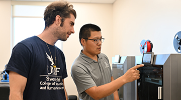 Dr. Longfei Zhou showing how to work a 3D printing machine to student
