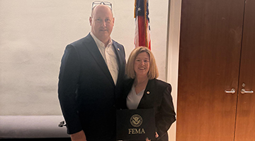 Amber Gazdick and John Hale standing together holding a FEMA plaque