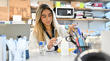 Anne Araujo putting a solution in a bottle in a lab