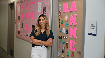 Anne Araujo standing in front of her decorated residence hall room door