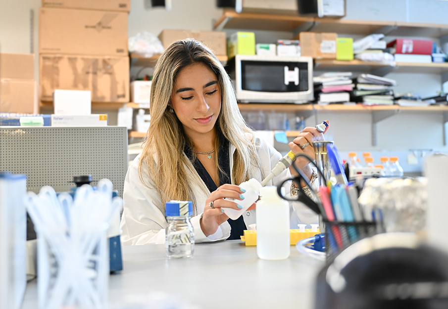 Anne Araujo putting a solution in a bottle in a lab