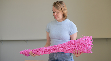 Emily Bailey holding art piece made of toy pink soldiers