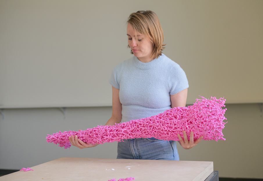 Emily Bailey holding art piece made of toy pink soldiers